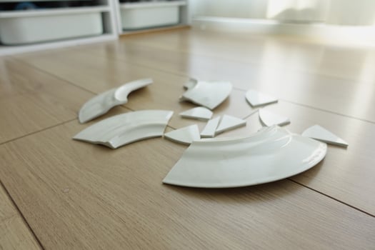 Fragments of broken ceramic scattered on wooden floor photo