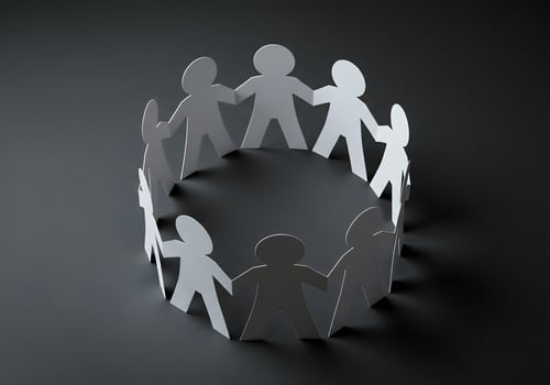 Paper people holding hands in a circle on a black background photo