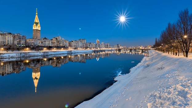 Winter Night Scene with Snow Covered River and Illuminated Cityscape Under Full Moon photo