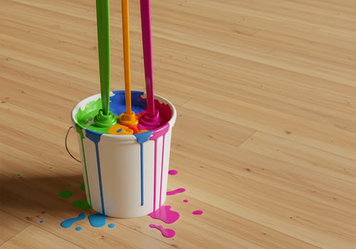 A bucket of paint with colorful paint on the floor photo
