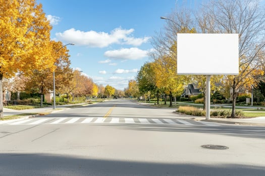 Calm suburban street with trees in autumn, clear blue sky, and empty billboard space. photo