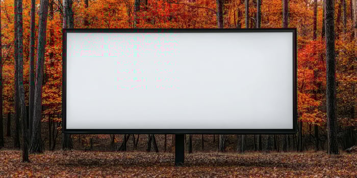 Blank billboard surrounded by vibrant autumn trees in a peaceful forest setting. photo