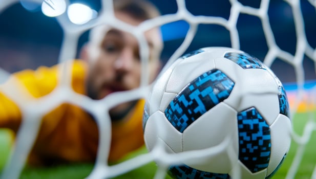 Goalkeeper reaches for ball during match. A goalkeeper dives to save a soccer ball during an intense competitive match under stadium lights. photo
