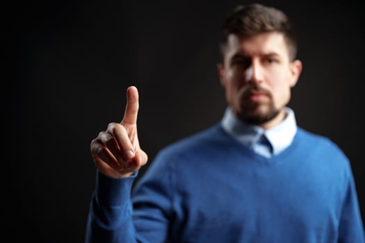 Man in blue sweater raising finger in a gesture of importance during a dramatic moment photo