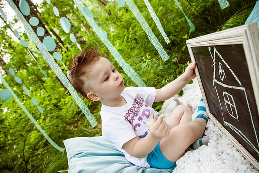khabarovsk, russia,28.08.2013. A young boy is sitting on a blanket in a forest, holding a chalkboard photo