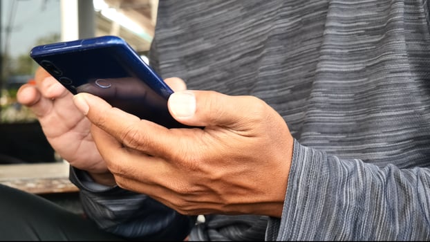 A man is using his phone while sitting outside photo