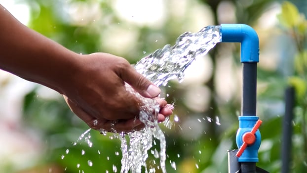 A person is holding a hose that is being filled with water photo