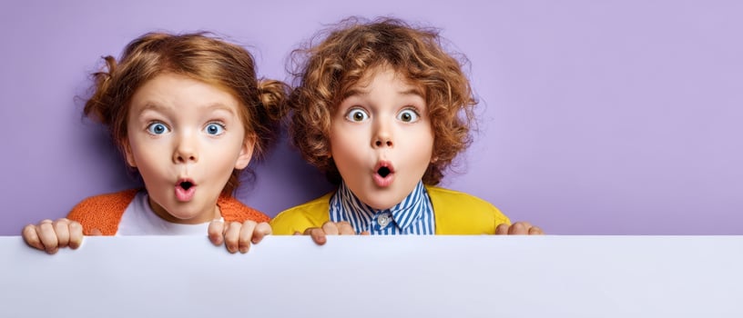 The surprised children showing excitement and joy behind a blank banner. photo