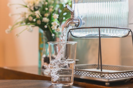 Water is poured into a glass from a manual water dispenser. photo