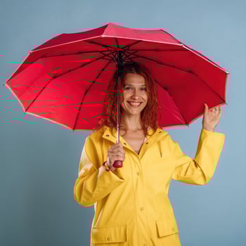 A woman in a yellow raincoat holding an umbrella photo