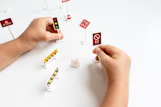 Child playing with toy traffic signs on white background photo