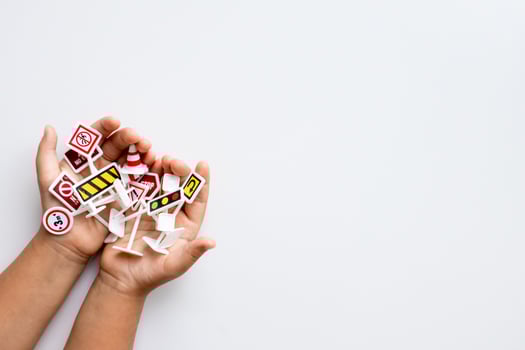 Children hands holding toy traffic signs on white background photo