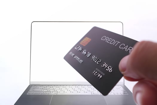 Online payment with credit card held in hand in front of laptop screen, secure digital transaction. photo