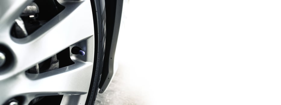 Close-up of race alloy wheel and tire with valve stem of car, blank copy space on white background photo