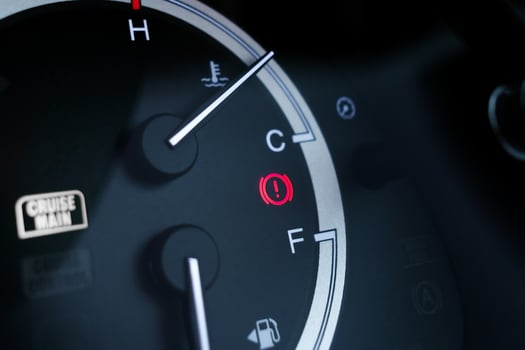 Red brake system warning light on car dashboard next to fuel and temperature gauge indicators. photo