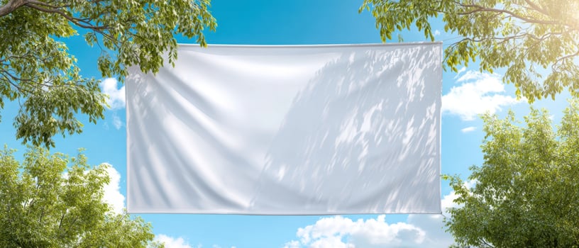 The blank white banner suspended between trees under a bright blue sky photo