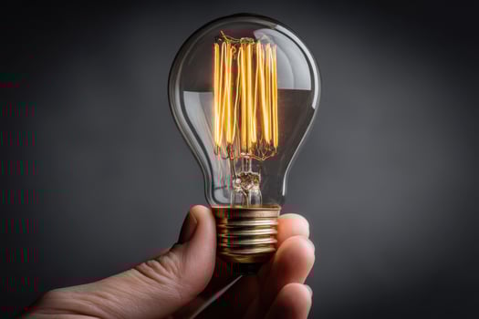 A hand holding a light bulb on a dark background photo