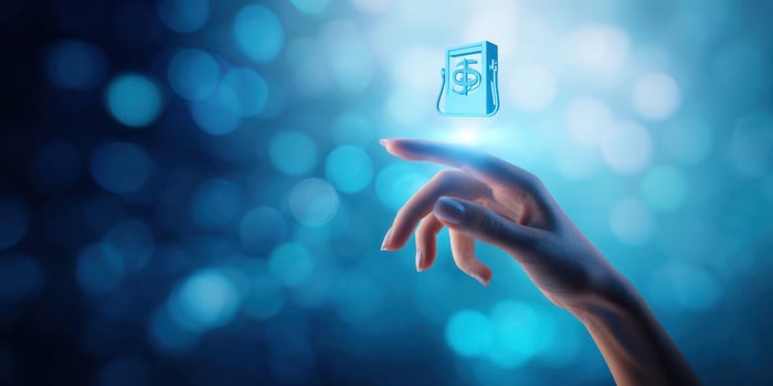 The hand reaching towards a floating digital finance icon in blue light. photo