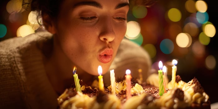 The woman blowing out candles on a beautifully decorated birthday cake. photo