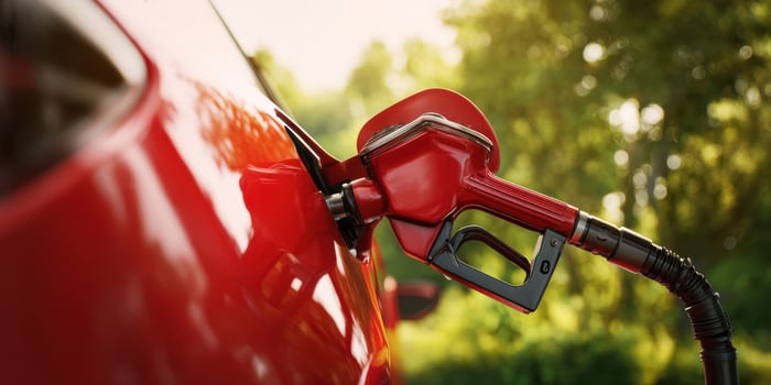 The red fuel nozzle connected to a car in a natural outdoor setting. photo