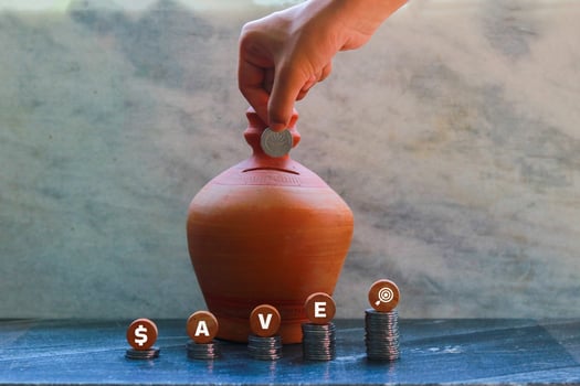 Hand putting a coin into a Soil Bank with the word Save closeup photo