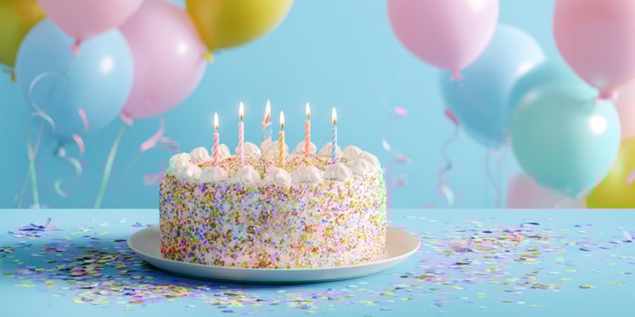The colorful birthday cake decorated with candles and festive balloons in the background. photo