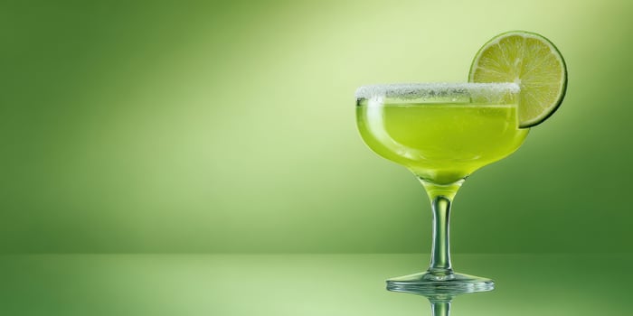 The vibrant margarita glass with a lime slice on a glossy surface. photo