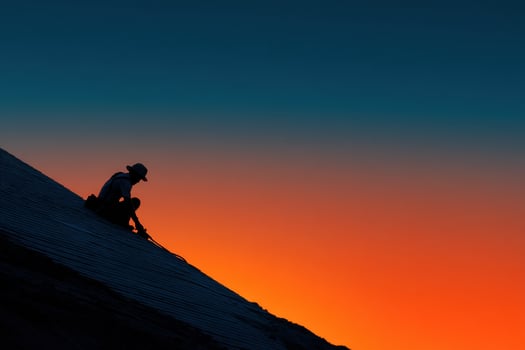 A man sitting on the roof of a building at sunset photo