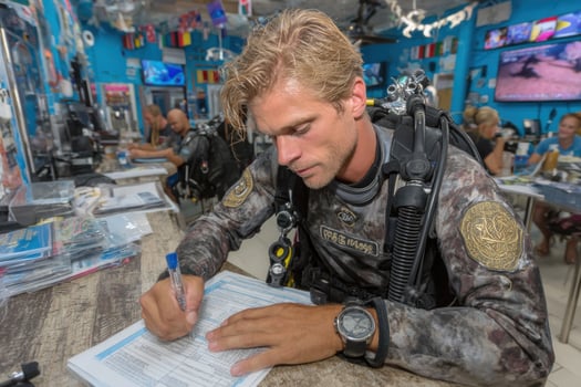 A man in scuba gear signing a document photo