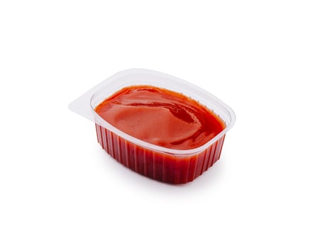 Bright red condiment in a small plastic container for savory dishes photo