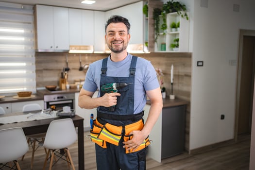 Handyman smiling and holding cordless drill in kitchen photo