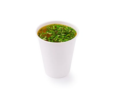 Warm herbal drink in a white cup with fresh green herbs on top photo