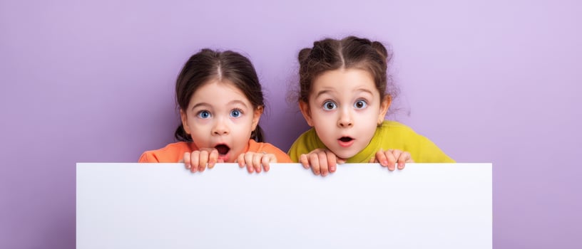 The surprised expressions of two girls holding a blank sign in a playful setting. photo