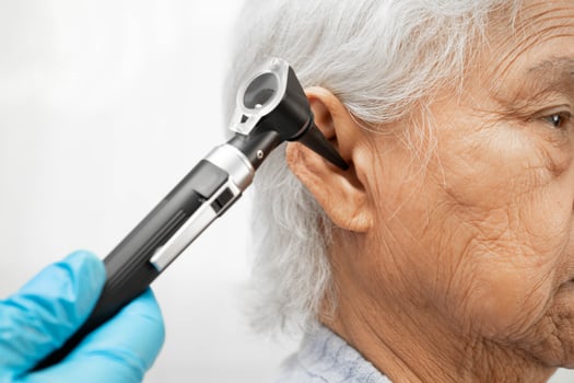 Otolaryngologist or ENT physician doctor examining senior patient ear with otoscope, hearing photo