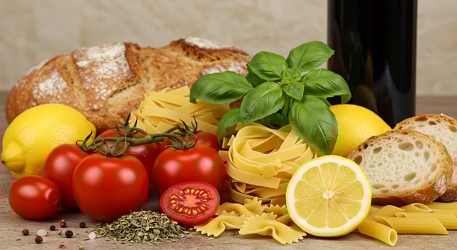 A table with pasta, tomatoes, bread, and a bottle of wine photo
