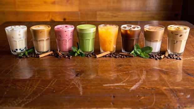 Variety of colorful iced coffee and bubble tea drinks lined up on a wooden table photo