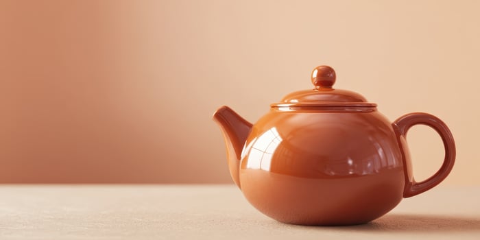 The ceramic teapot in warm tones on a simple surface. photo