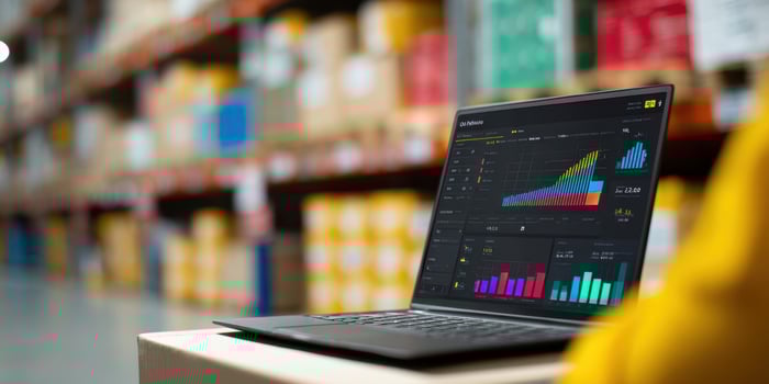 The laptop displaying analytics metrics in a warehouse environment. photo
