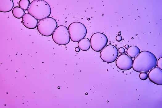 The texture of a cosmetic serum with a trail of bubbles on a purple background. photo