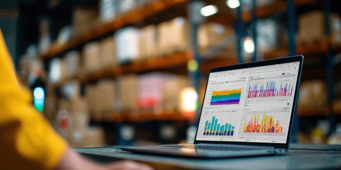 The laptop displaying colorful data analytics in a busy warehouse environment photo