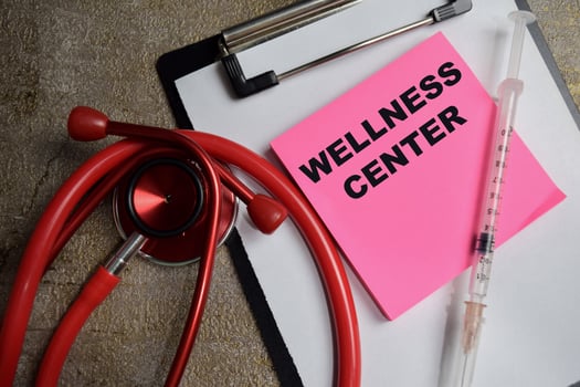 Concept of Wellness Center write on sticky notes isolated on Wooden Table. healthcare and pharmaceutical concept photo