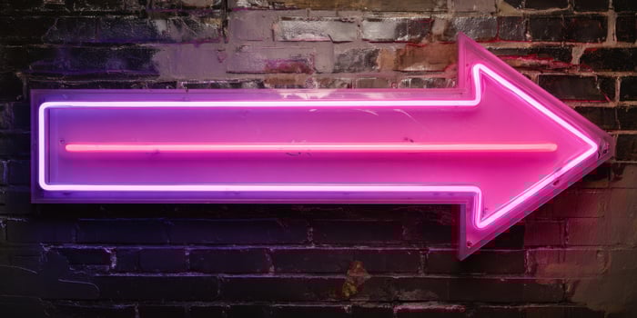 The vibrant neon arrow illuminating a dark urban wall. photo