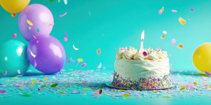 The colorful birthday cake surrounded by balloons and confetti in a festive setting. photo