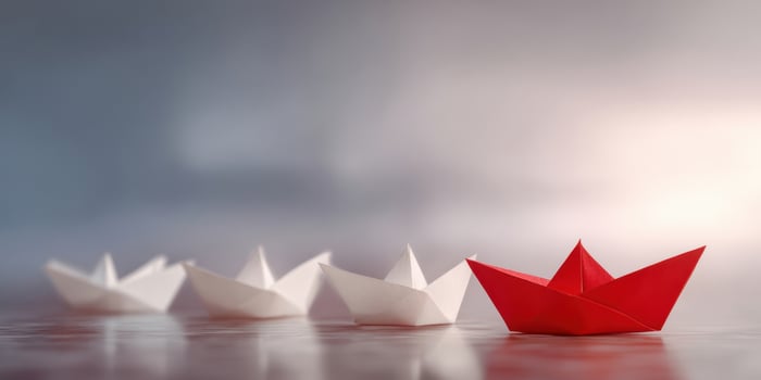 The red origami boat standing out among white paper boats photo