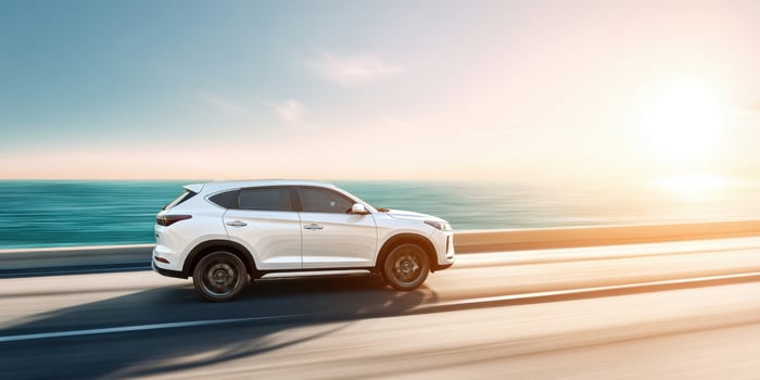 The sleek SUV driving along a stunning coastal road at sunset. photo