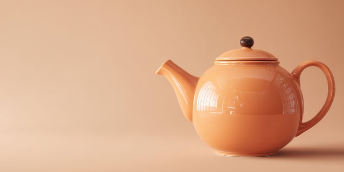 The elegant orange teapot with a minimalist design on a soft background. photo