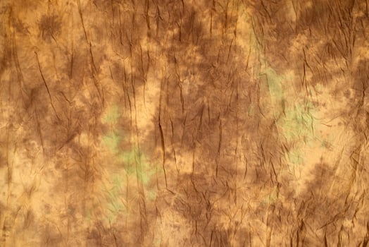 Brown and beige wrinkled fabric texture with subtle green stains, abstract background for design, vintage or grunge style photo