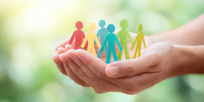 The hands holding diverse paper figures representing community and support. photo