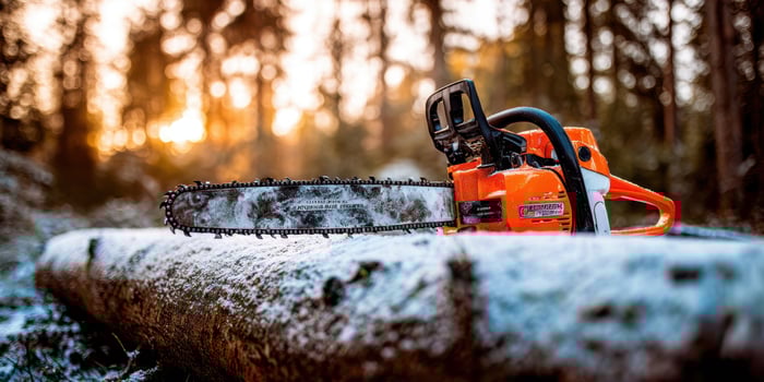 The chainsaw resting on a snowy log in a serene forest at sunrise. photo