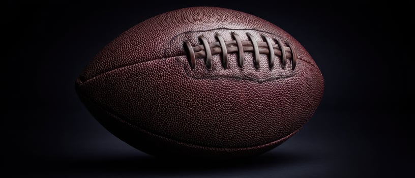 The classic brown football on a dark background showcasing its unique texture. photo